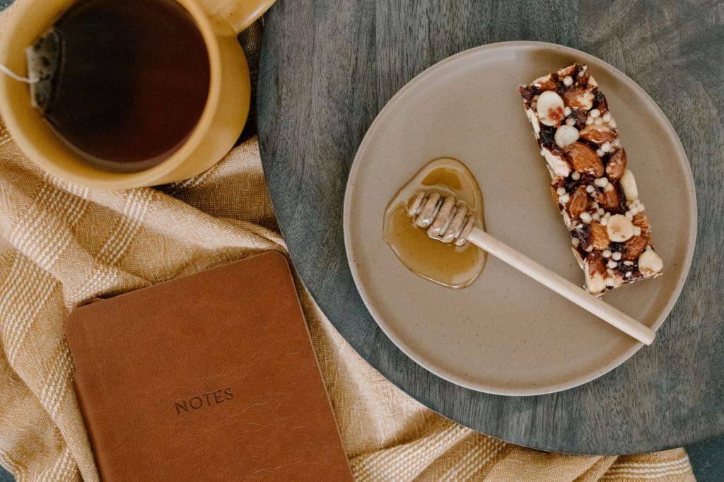 Nut bar on a plate next to a cup of tea and honey