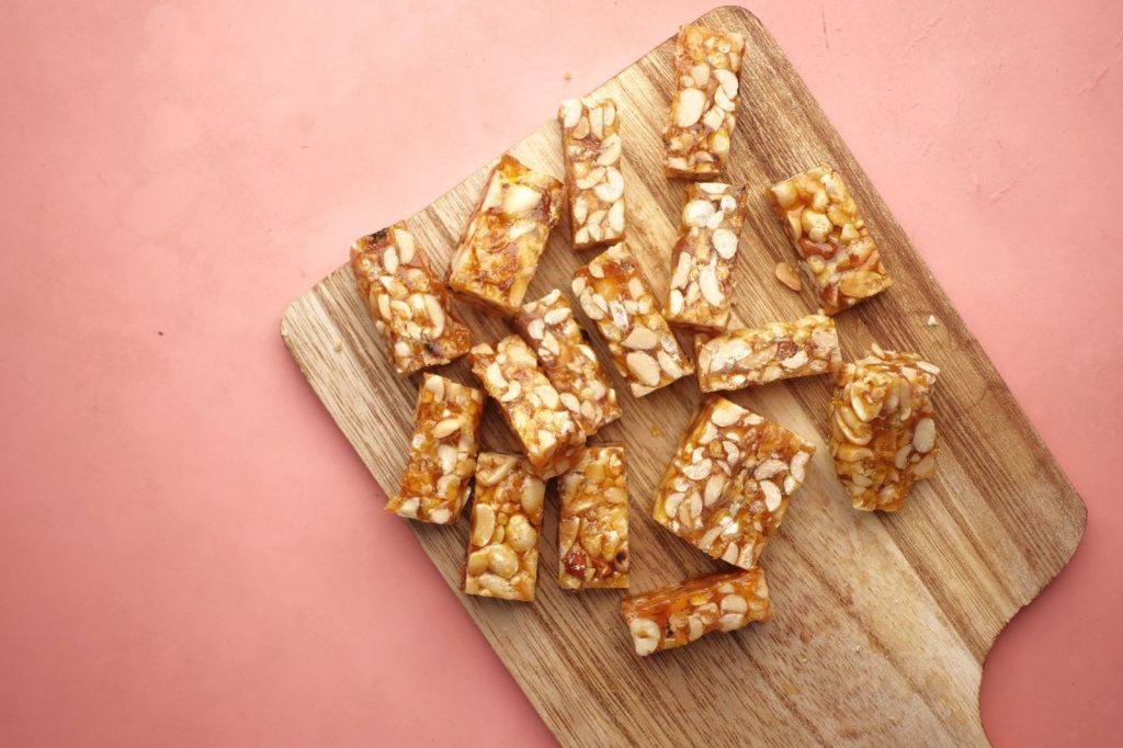 Pieces of nut and fruit bar on a wooden board