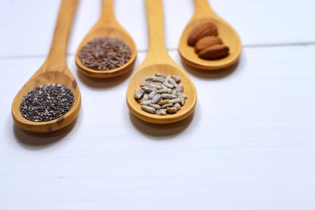 Wooden spoons with chia seeds, sunflower seeds and almonds